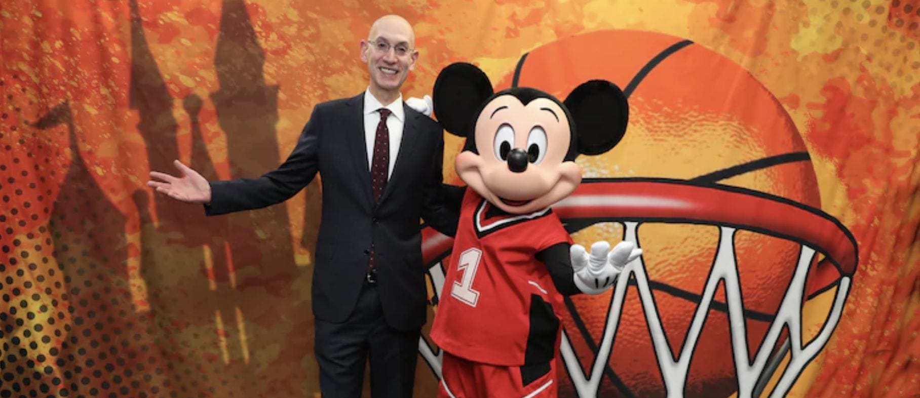 Foto divulgada pela NBA para falar da possibilidade de retomar a temporada no complexo da Disney Foto divulgada pela NBA com o coordenador da liga ao lado do Mickey, vestido com roupa de basquete, o castelo da Cinderela e uma bola de basquete ao fundo.